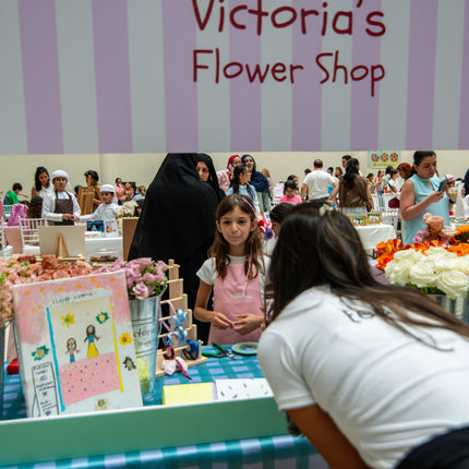 Children's flower shop booth at an event with 'Victoria's Flower Shop' sign.